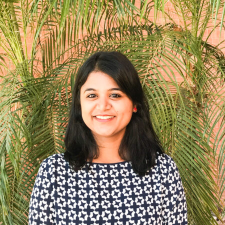 Gayathri Padmaa Sankaranarayanan, Senior Consultant at Ponaman Healthcare Consulting, smiling in front of tropical foliage, showcasing her professional background in healthcare analytics and consulting.